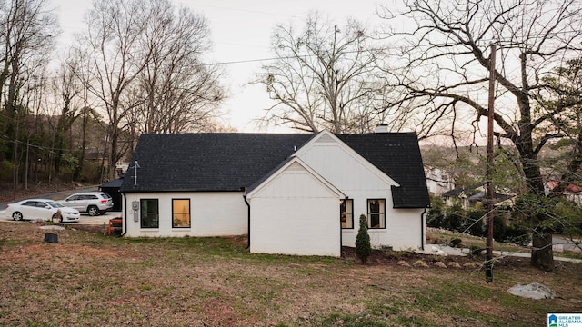 view of front of property with a front yard, brick siding, roof with shingles, and a chimney