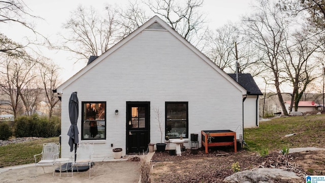 rear view of property with brick siding and roof with shingles
