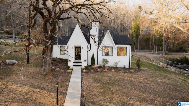 view of front of property with a shingled roof, a chimney, and fence