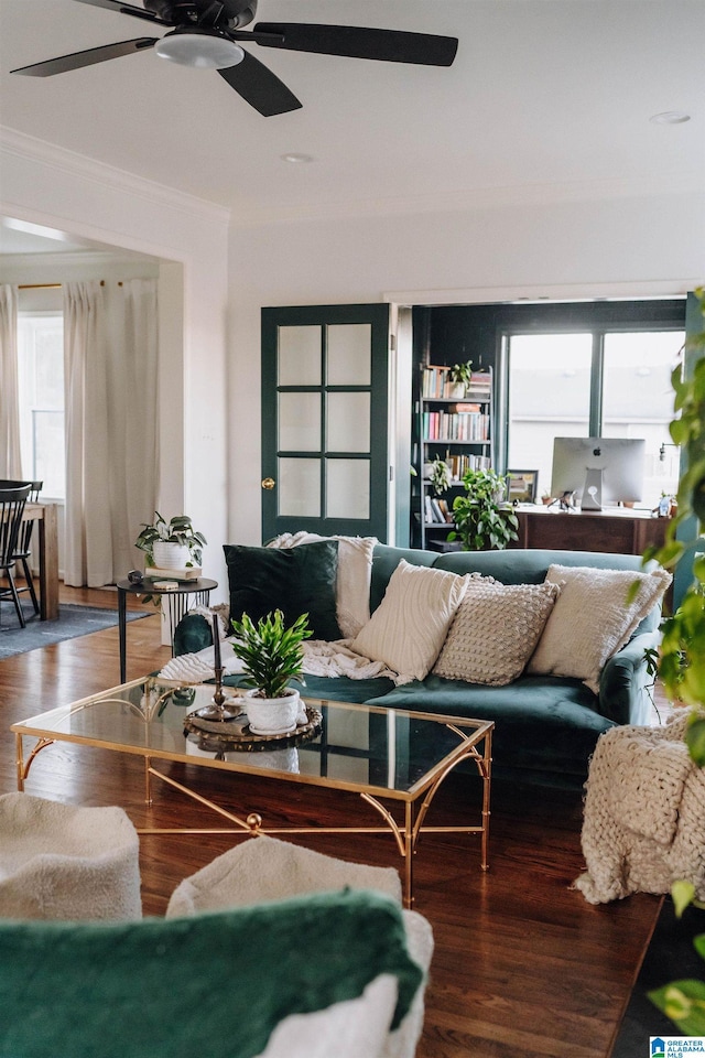 living area with wood finished floors, a ceiling fan, and ornamental molding