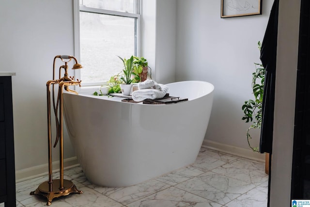 full bathroom with a freestanding tub, baseboards, and marble finish floor