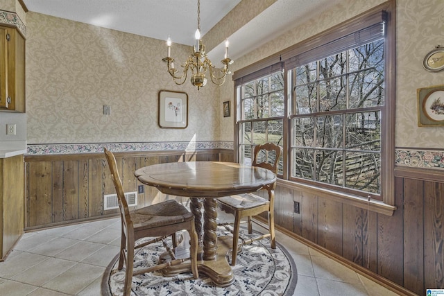 dining room featuring visible vents, wallpapered walls, light tile patterned floors, wainscoting, and an inviting chandelier