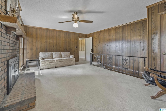 carpeted living area with a textured ceiling, wooden walls, a fireplace, and ceiling fan