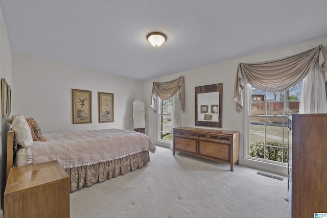 carpeted bedroom with visible vents and a textured ceiling