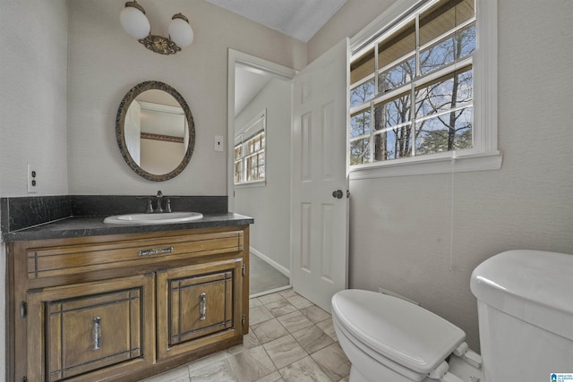 half bathroom with vanity, toilet, and marble finish floor