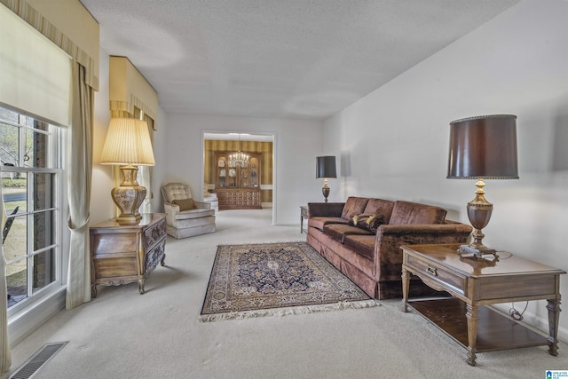 carpeted living room with a notable chandelier, visible vents, and a textured ceiling