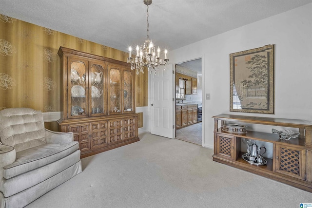 living area with a chandelier, light colored carpet, beverage cooler, and a textured ceiling