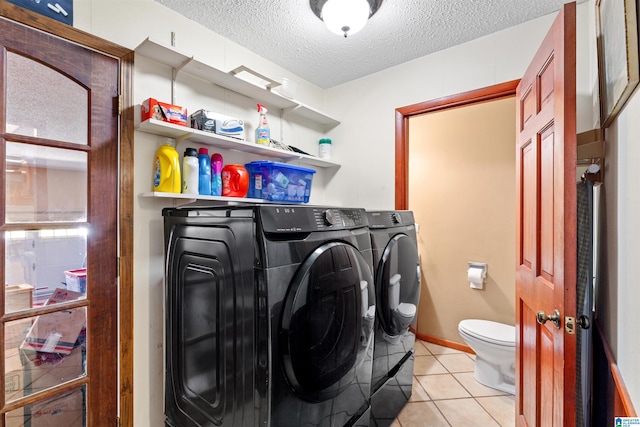 washroom featuring light tile patterned floors, a textured ceiling, washing machine and dryer, and laundry area