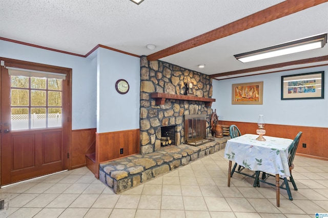 dining area featuring a wainscoted wall, a textured ceiling, a stone fireplace, and wood walls