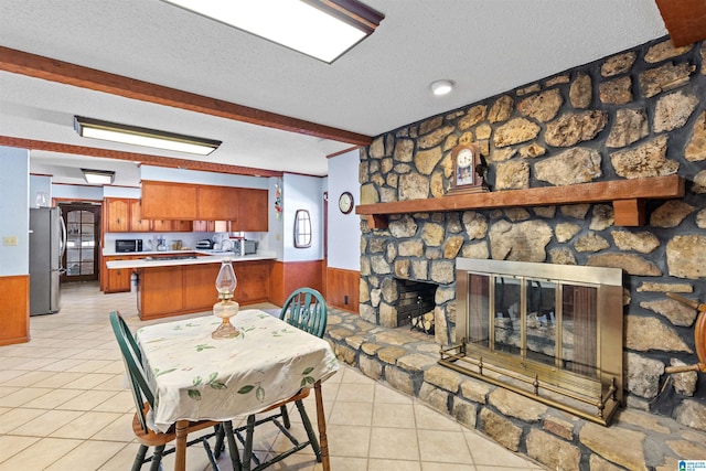 dining space featuring light tile patterned floors, a wainscoted wall, and a textured ceiling