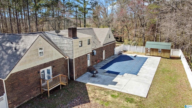 exterior space featuring an outbuilding, a patio, a fenced backyard, brick siding, and a chimney