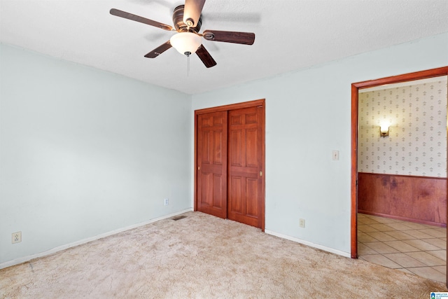 unfurnished bedroom featuring visible vents, carpet flooring, a ceiling fan, and a closet