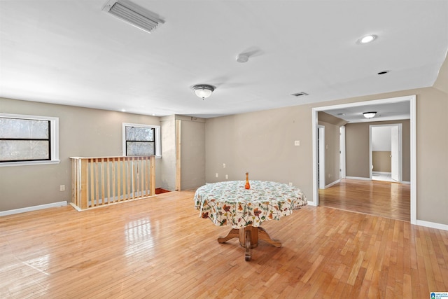 living area featuring a wealth of natural light, visible vents, light wood-type flooring, and baseboards