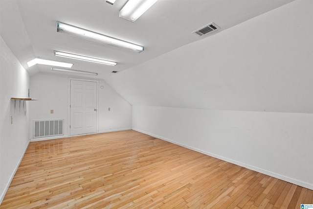 bonus room featuring visible vents, vaulted ceiling with skylight, and hardwood / wood-style floors