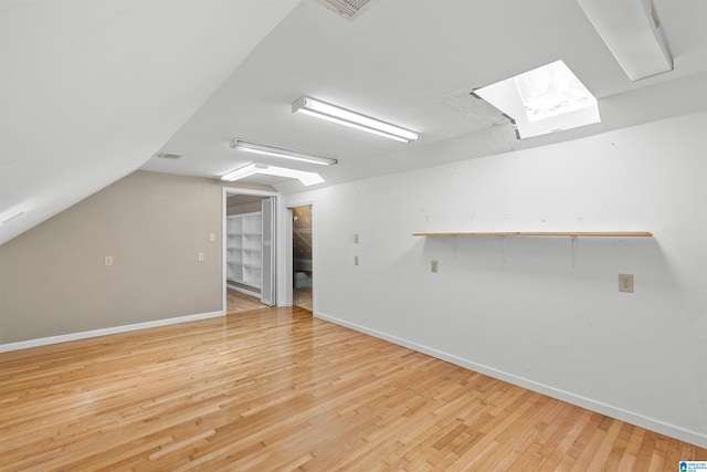 bonus room featuring baseboards, lofted ceiling with skylight, and light wood finished floors