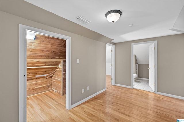 unfurnished bedroom with visible vents, ensuite bathroom, light wood-type flooring, and baseboards