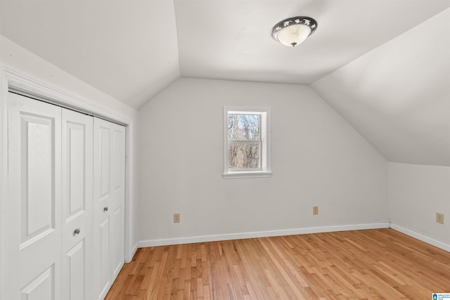 bonus room with light wood finished floors, baseboards, and vaulted ceiling