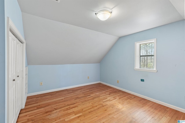 additional living space with vaulted ceiling, light wood-style floors, and baseboards