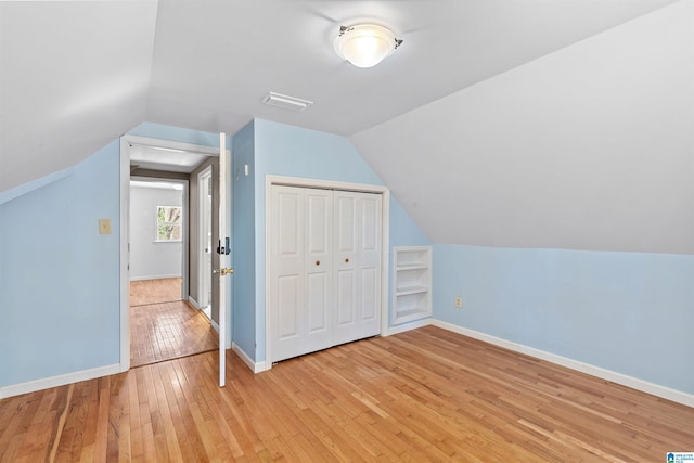 additional living space with visible vents, baseboards, lofted ceiling, and light wood-style floors