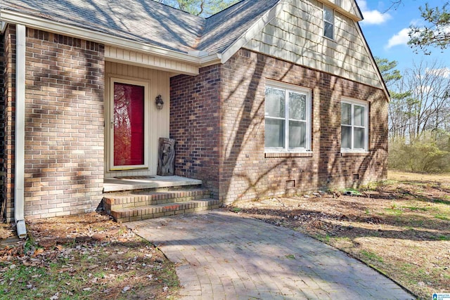 entrance to property with crawl space, brick siding, and roof with shingles