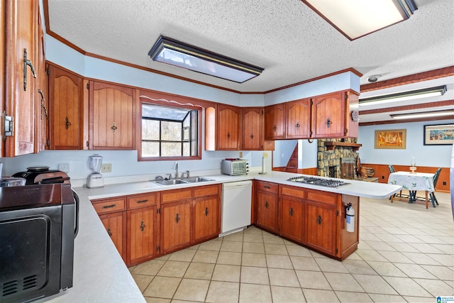 kitchen featuring gas cooktop, brown cabinetry, a peninsula, white dishwasher, and a sink