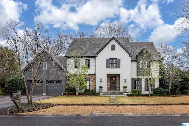 view of front facade with a front yard, brick siding, driveway, and a shingled roof