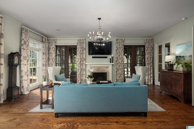 living area featuring wood finished floors, a chandelier, a fireplace, and ornamental molding