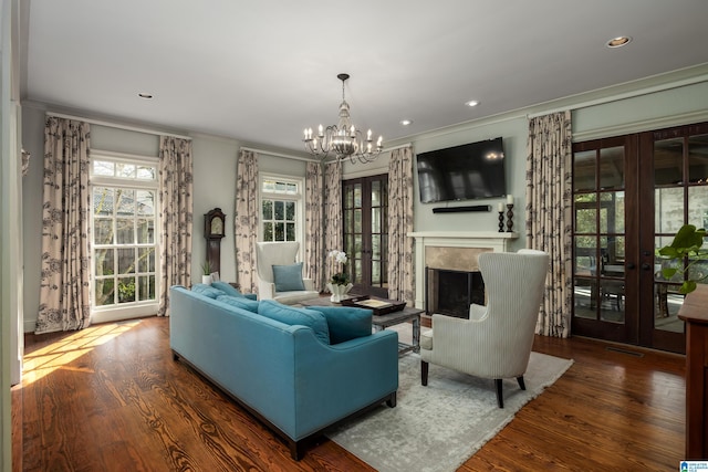 living area with french doors, wood finished floors, a high end fireplace, and a chandelier