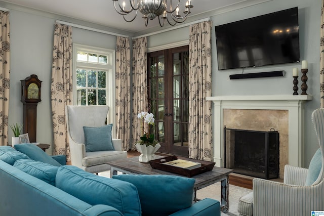 living area featuring ornamental molding, a fireplace, an inviting chandelier, and wood finished floors