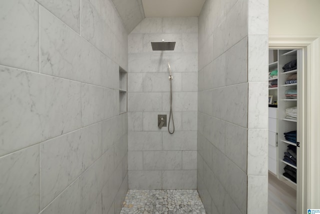 full bathroom featuring a spacious closet and a tile shower