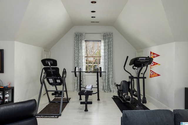 workout room with visible vents, wood finished floors, baseboards, and vaulted ceiling