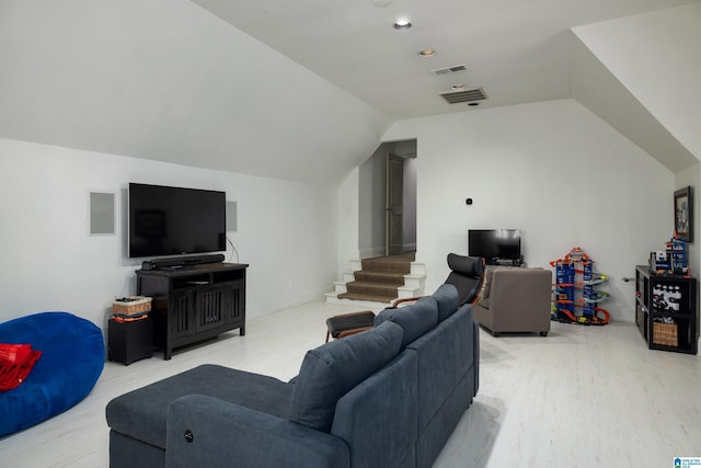 living area with light wood finished floors, visible vents, stairway, and vaulted ceiling