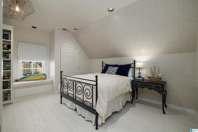 bedroom with visible vents, wood finished floors, baseboards, a chandelier, and vaulted ceiling