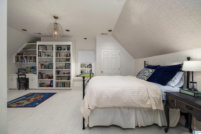 bedroom with vaulted ceiling, visible vents, and wood finished floors