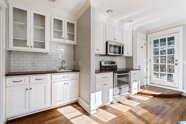 kitchen with glass insert cabinets, stainless steel appliances, wood finished floors, white cabinetry, and a sink