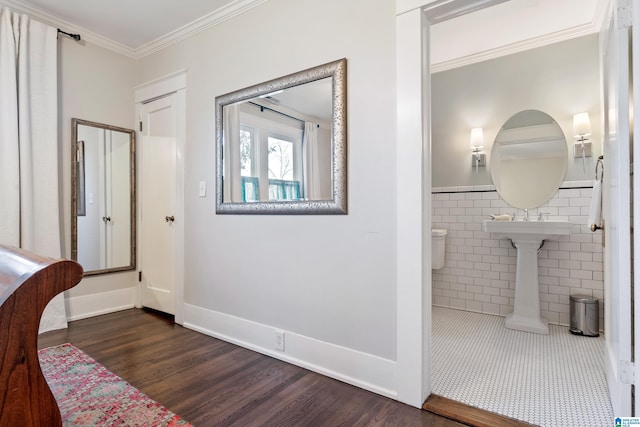 corridor with wood finished floors, wainscoting, tile walls, and ornamental molding