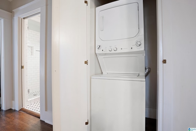 washroom featuring stacked washer / drying machine, dark wood-type flooring, and laundry area