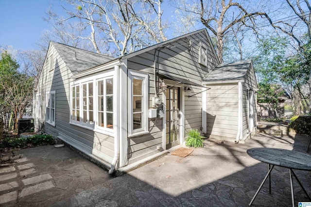 exterior space with a patio area and roof with shingles