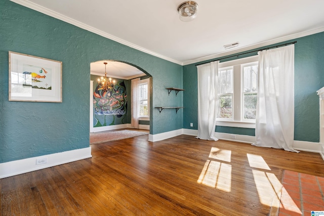 unfurnished room with arched walkways, a healthy amount of sunlight, and a textured wall