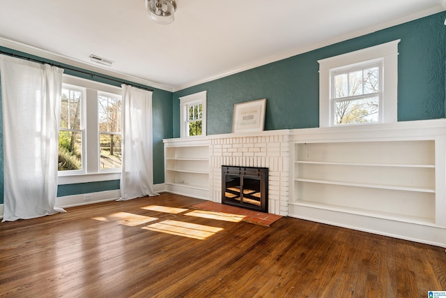 unfurnished living room with visible vents, a brick fireplace, crown molding, and hardwood / wood-style flooring