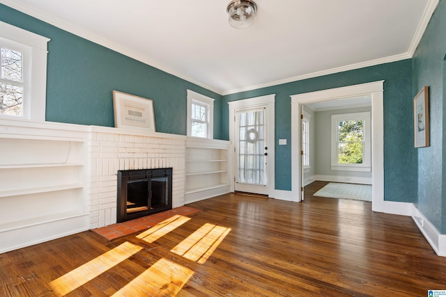 unfurnished living room featuring wood finished floors, a fireplace, crown molding, baseboards, and a textured wall