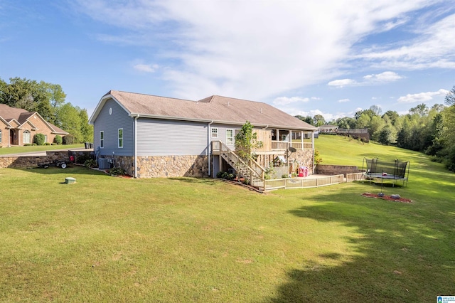 back of property featuring central air condition unit, stone siding, a trampoline, a yard, and stairs