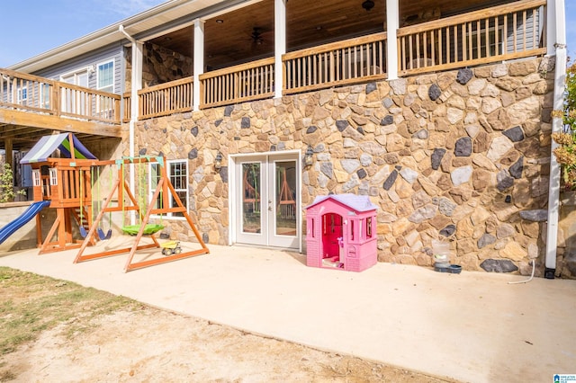 exterior space with a balcony, a playground, french doors, and stone siding