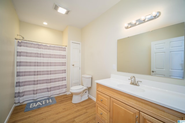 bathroom with vanity, wood finished floors, visible vents, baseboards, and toilet