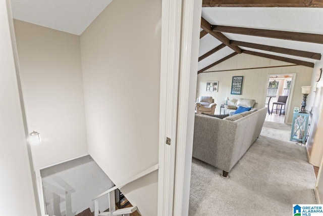 carpeted living area with vaulted ceiling with beams