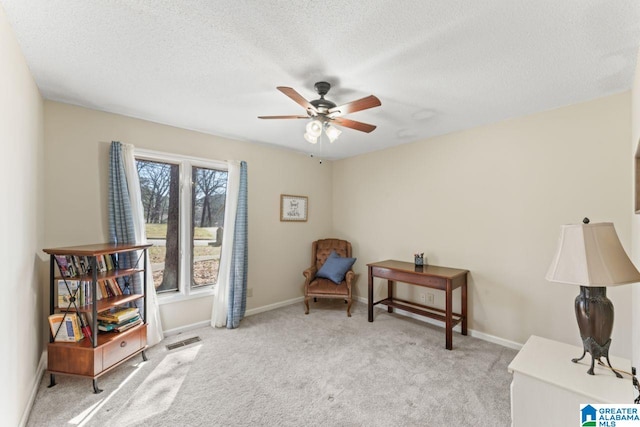 living area featuring a textured ceiling, baseboards, a ceiling fan, and carpet floors