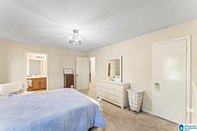 bedroom featuring light carpet, a textured ceiling, ensuite bath, and an inviting chandelier