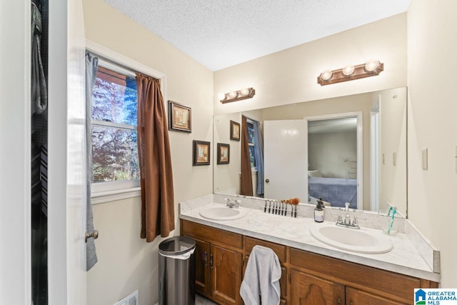 bathroom featuring a sink, a textured ceiling, and double vanity