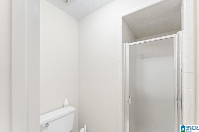 full bath featuring toilet, a stall shower, and a textured ceiling