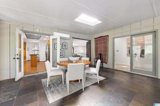 dining room featuring stone tile floors and a wall unit AC